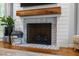 Close up on fireplace with brick surround, wood mantle, and shiplap detailing at 1013 New Chester Ct, Apex, NC 27502