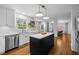 Open concept kitchen with stainless steel appliances, white cabinetry, hardwood floors, and kitchen island at 1013 New Chester Ct, Apex, NC 27502