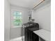 Modern laundry room featuring a dark washer and dryer, storage shelves, and a bright window at 1013 New Chester Ct, Apex, NC 27502