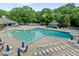 Community pool featuring lounge chairs, tables with umbrellas, mature trees, and an adjacent clubhouse at 1013 New Chester Ct, Apex, NC 27502