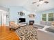 Bright living room featuring a fireplace, ceiling fan, a gray sectional sofa, and hardwood floors with area rug at 102 Heritage Ridge Ct, Knightdale, NC 27545