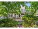 Backyard view showcases the back of the house and wooden deck with outdoor seating through lush green trees at 1025 Kingsway Dr, Apex, NC 27502