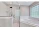 Bright bathroom featuring a tub and separate glass-enclosed shower and a window with glass blocks at 105 Wittenham Dr, Cary, NC 27519