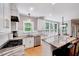 Open kitchen with white cabinets, stone counters, island seating, and stainless appliances at 105 Wittenham Dr, Cary, NC 27519