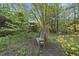 Backyard view featuring mature trees, blooming foliage, and a charming bench at 13 Crosswinds Estates Dr, Pittsboro, NC 27312
