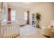 Well-lit Bedroom with a crib, dresser, bookshelf, and chair at 134 Cotten Dr, Morrisville, NC 27560