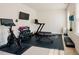 Brightly lit home gym features exercise bike, treadmill, weight rack, TV and rubber flooring at 134 Cotten Dr, Morrisville, NC 27560