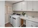 Well-organized laundry room with white cabinets, counter space, sink, and modern washer and dryer at 1412 Main St, Lillington, NC 27546