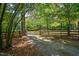 Long gravel driveway leads to a wooded property with a split-rail fence at 1608 New Hill Olive Chapel Rd, Apex, NC 27502