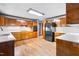 Traditional kitchen with wood cabinets, tile backsplash, wood flooring, and modern black appliances at 1608 New Hill Olive Chapel Rd, Apex, NC 27502