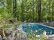 A serene swimming pool with a wooden deck surrounded by lush greenery at 1608 New Hill Olive Chapel Rd, Apex, NC 27502
