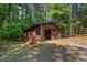 Exterior view of a wooden storage shed with an open door and a well-maintained lawn at 1608 New Hill Olive Chapel Rd, Apex, NC 27502