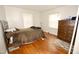Spacious bedroom with wood floors, a bed with brown covers, a large dresser, and windows for natural light at 1620 Old Wilson Rd, Rocky Mount, NC 27801