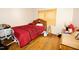 A cozy bedroom featuring wood floors, a bed with red covers, and a window for natural light at 1620 Old Wilson Rd, Rocky Mount, NC 27801