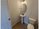 Compact bathroom featuring a pedestal sink, oval mirror, toilet, and contemporary lighting fixtures at 188 Tuskeegee Dr, Smithfield, NC 27577