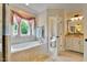 Bright bathroom with garden tub, stone tilework, framed window with elegant valance, and granite countertop at 1927 Napoli Dr, Apex, NC 27502
