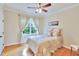 Cozy bedroom features hardwood floors, ceiling fan, natural light, and cream colored walls at 1927 Napoli Dr, Apex, NC 27502