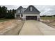 Two-story home with gray siding, stone accents, an attached garage, and a long concrete driveway at 202 Tuskeegee Dr, Smithfield, NC 27577