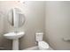 Modern powder room featuring a pedestal sink, round mirror, and neutral color scheme at 219 Rosedale Creek Dr, Durham, NC 27703
