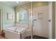 Bathroom featuring a large soaking tub, glass shower, and natural light, ideal for relaxation and comfort at 2212 Plowridge Rd, Fuquay Varina, NC 27526