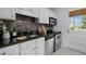 Well-lit kitchen features white cabinets, stone backsplash, stainless steel appliances, and tiled floors at 2331 Bernard St, Raleigh, NC 27608