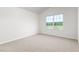 Bedroom with neutral carpet, white walls, and a large window overlooking the front yard at 236 Moyer Dr, Graham, NC 27253