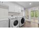 Bright laundry room with modern washer and dryer units and white cabinets for storage at 237 Jason Way, Youngsville, NC 27596