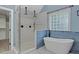 Elegant bathroom featuring a glass-enclosed shower, soaking tub, and stylish blue accents at 244 Mantle Dr, Clayton, NC 27527
