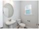 This powder room features a pedestal sink, an oval mirror, and a window for natural light at 263 Hopewell Branch Ct, Smithfield, NC 27577