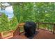 The outdoor deck has wood rails and is home to a barbeque grill in front of a wooded view at 2633 Beckwith Rd, Apex, NC 27523