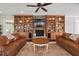 Inviting living room showcasing custom built-ins, a stone fireplace, and warm leather sofas, perfect for relaxation and entertainment at 2633 Beckwith Rd, Apex, NC 27523