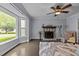 Bright living room with a cozy fireplace, bay window, ceiling fan, and hardwood floors at 2705 Kempsford Pl, Raleigh, NC 27604