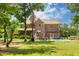 Expansive backyard showcasing the brick home, pool, pergola, mature trees, and plenty of green space at 2912 Turning Brook Ln, Raleigh, NC 27616