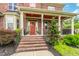 Charming brick home featuring a red front door, landscaping, and covered porch at 2912 Turning Brook Ln, Raleigh, NC 27616