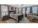 Neutral main bedroom showcases large bed, dark wood nightstands and sitting area with light streaming through the windows at 303 Leighann Ridge Ln, Rolesville, NC 27571