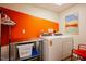 Bright laundry room featuring a washer, dryer, shelving, and a vibrant accent wall at 3911 Morvan Way, Raleigh, NC 27612