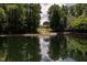 Scenic pond reflecting an estate home surrounded by lush greenery and a fountain at 4038 Carpenter Pond Rd, Durham, NC 27703