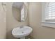 Powder room featuring pedestal sink, round mirror and neutral color scheme at 436 Edgepine Dr, Holly Springs, NC 27540