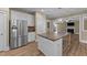 Kitchen island with stone countertop, stainless steel refrigerator, and easy access to living spaces at 436 Edgepine Dr, Holly Springs, NC 27540