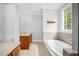 Bright bathroom featuring a large garden tub with tile surround and double vanity with stone countertops at 4874 Thom Rd, Mebane, NC 27302