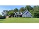 Inviting blue two-story home with white trim, dormers and a brick side porch on a lush green lawn at 4874 Thom Rd, Mebane, NC 27302