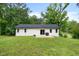 Home's backyard featuring a well-maintained lawn, patio, and privacy from mature trees at 5020 Mimosa Dr, Durham, NC 27713
