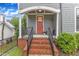 Charming front porch with brick steps, white columns, and a welcoming orange door at 511 Hamilton Cottage Way, Raleigh, NC 27605