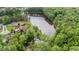 Aerial view of lakefront property with lush trees surrounding the lake and two houses at 5308 Stableview Ct, Holly Springs, NC 27540
