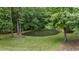 Picturesque pond surrounded by lush greenery, tall trees, and a well manicured lawn at 5308 Stableview Ct, Holly Springs, NC 27540