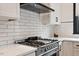 Stainless steel range and vent hood with quartz countertops and subway tile backsplash at 610 Velma Hopkins Ln, Raleigh, NC 27603