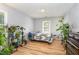 Bright bedroom with hardwood floors, filled with sunlight from the window and decorated with numerous healthy green plants at 628 Kankakee Ct, Knightdale, NC 27545
