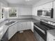Modern kitchen featuring white cabinets, stainless steel appliances, granite countertops, and wood-look flooring at 720 Rawls Dr, Raleigh, NC 27610
