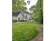 Expansive backyard featuring lush green lawn, mature trees, a patio area, and a charming deck with railing at 7517 Chippenham Ct, Raleigh, NC 27613