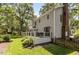 A spacious backyard with lush green grass, a wooden deck with outdoor seating, and mature trees for shade at 7517 Chippenham Ct, Raleigh, NC 27613